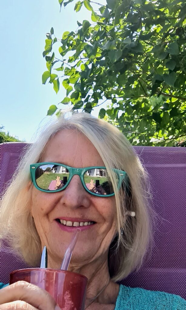 Kamniya Sonnenbrille trinkt Eiskaffee Frau mit verspiegelter Sonnenbrille trinkt aus rosa Glas mit Strohhalm